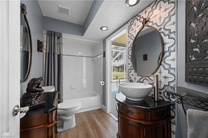Full bathroom with visible vents, toilet, wood finished floors, shower / bath combination with curtain, and vanity