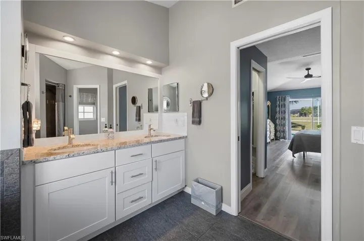 Ensuite bathroom with vaulted ceiling, double vanity, a sink, and baseboards