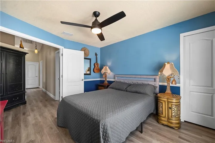 Bedroom featuring a textured ceiling, visible vents, wood finished floors, and a ceiling fan