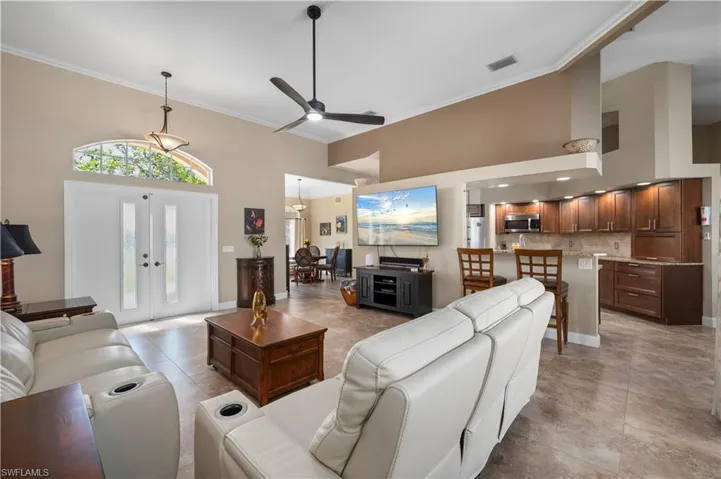 Living room with ornamental molding, french doors, and a high ceiling
