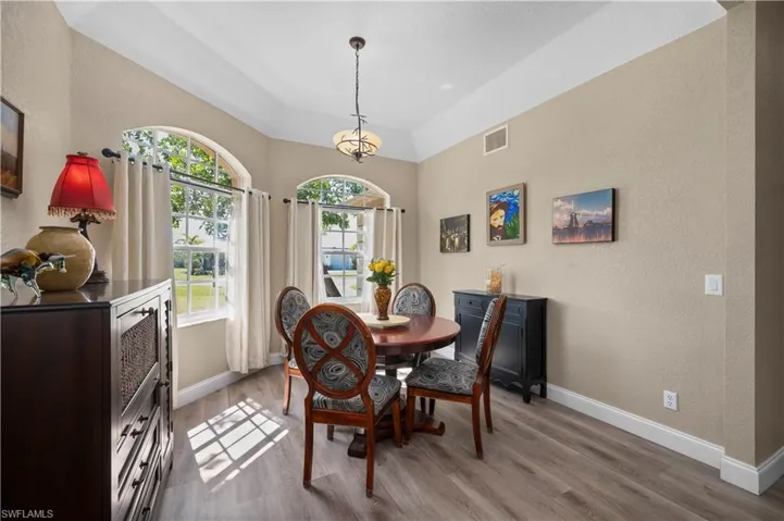 Dining space featuring light wood-style flooring, visible vents, baseboards, and a textured wall