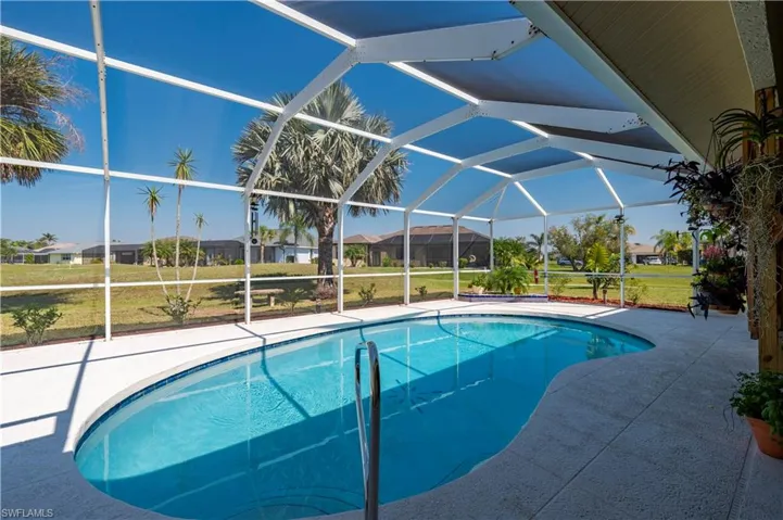Outdoor pool with glass enclosure, a lawn, and a patio