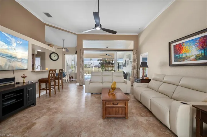 Living room featuring visible vents, crown molding, a high ceiling, and ceiling fan