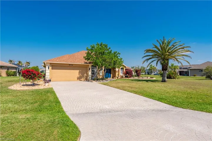 View of front facade with an attached garage, stucco siding, decorative driveway, and a front yard