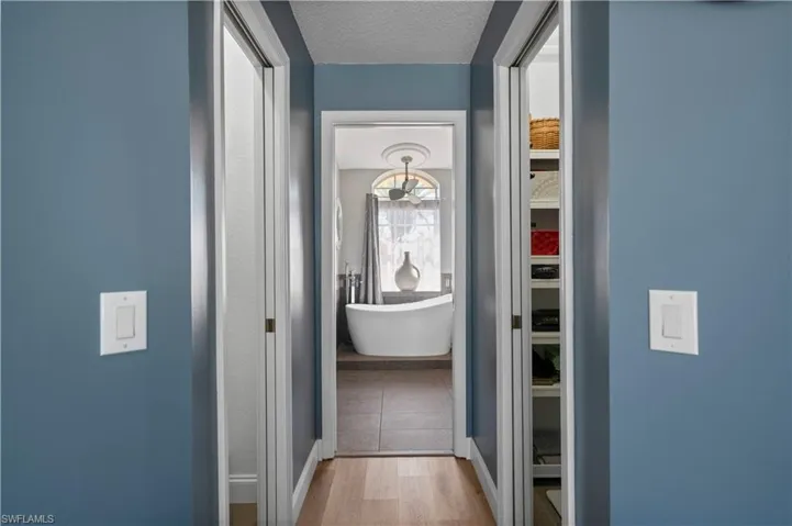 Hallway with a textured ceiling and wood finished floors