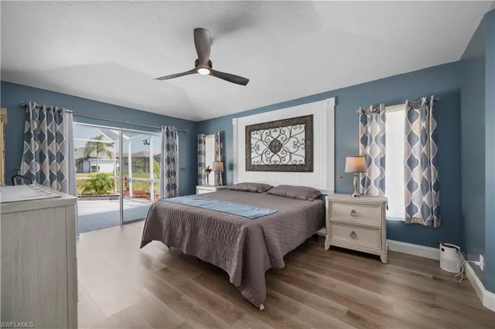 Bedroom with ceiling fan, access to outside, vaulted ceiling, and wood finished floors
