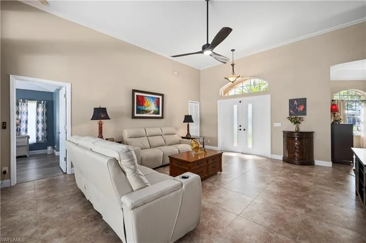 Living room with french doors, crown molding, a ceiling fan, baseboards, and tile patterned floors