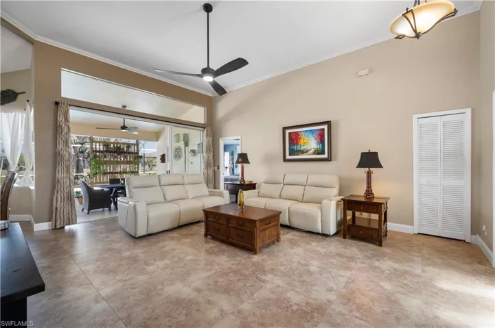 Living room with baseboards, a high ceiling, and crown molding