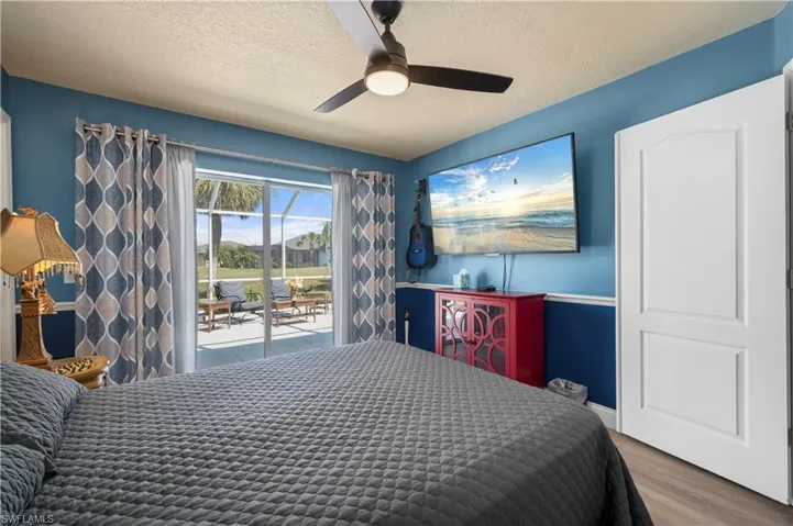 Bedroom with access to exterior, ceiling fan, a textured ceiling, and wood finished floors