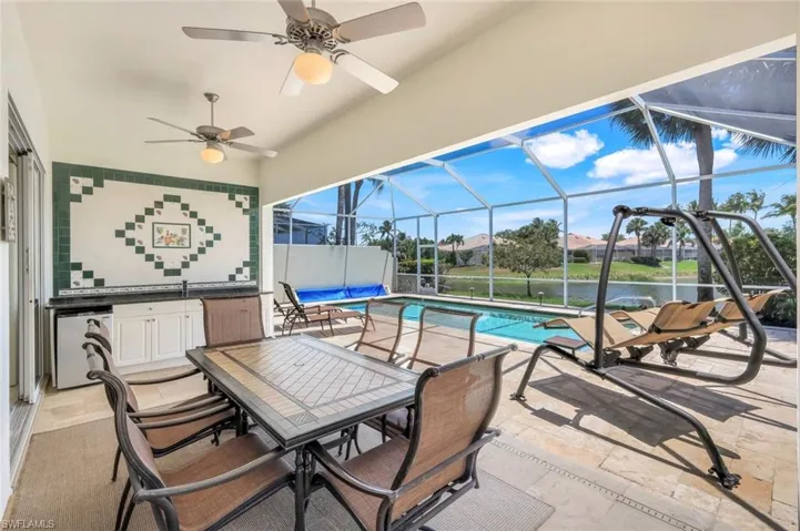 View of patio featuring ceiling fan, outdoor dining space, an outdoor pool, glass enclosure, and a water view