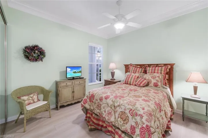 Bedroom with crown molding, light wood-type flooring, baseboards, and a ceiling fan