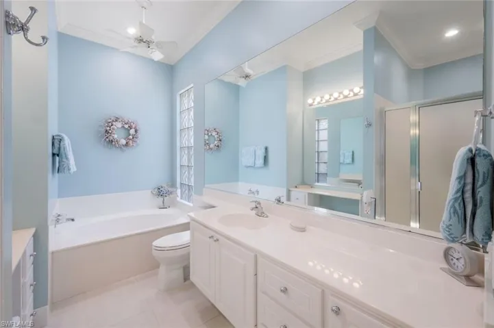 Bathroom featuring crown molding, ceiling fan, a shower stall, a bath, and tile patterned floors