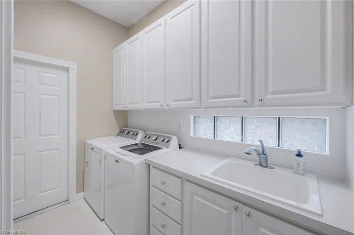 Washroom featuring cabinet space, washer and dryer, and light tile patterned flooring