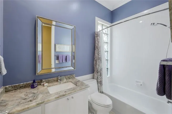 Full bath featuring toilet, vanity, shower / bathtub combination with curtain, and ornamental molding