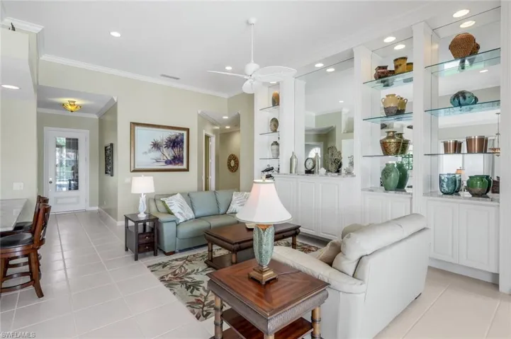 Living area featuring ornamental molding, light tile patterned floors, ceiling fan, recessed lighting, and built in shelves