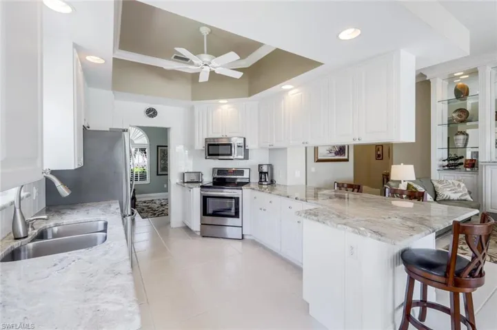 Kitchen with appliances with stainless steel finishes, a peninsula, a sink, a kitchen bar, and ceiling fan
