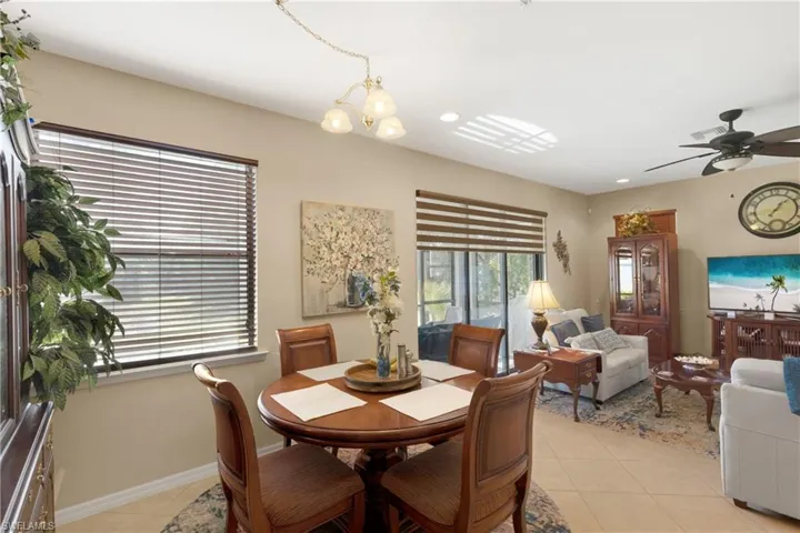 Tiled dining area with ceiling fan with notable chandelier