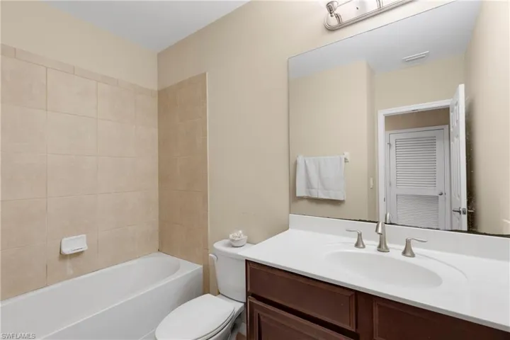 Full bathroom with vanity, tiled shower / bath combo, and toilet