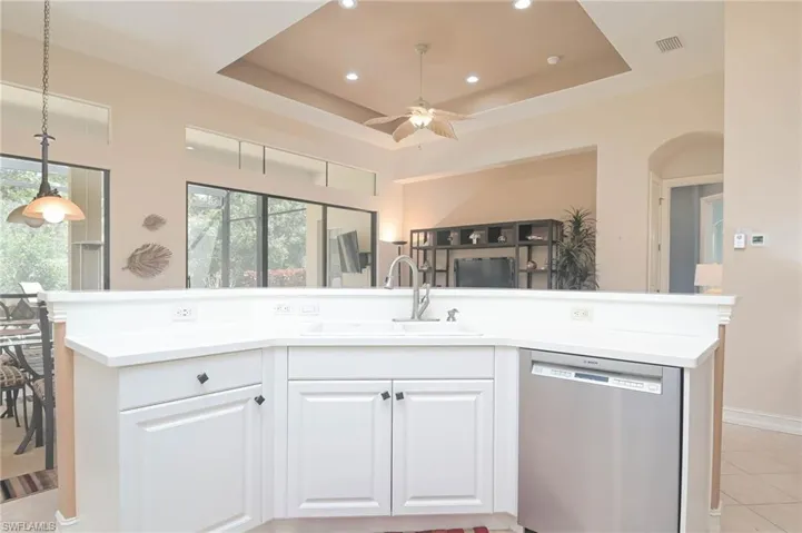 Kitchen featuring ceiling fan, dishwasher, a raised ceiling, and sink