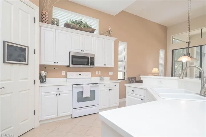 Kitchen featuring white range with electric stovetop, plenty of natural light, white cabinetry, and sink