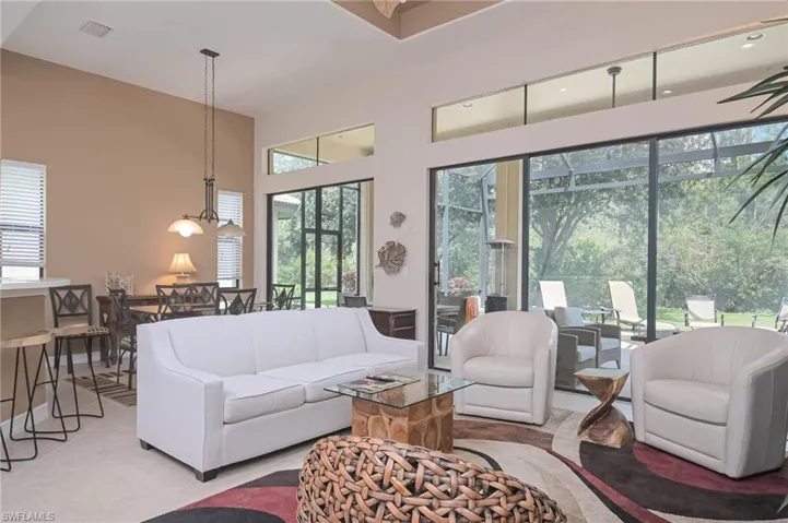 Tiled living room with plenty of natural light, a chandelier, and a high ceiling