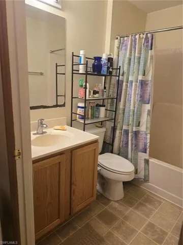 Full bathroom with tile patterned flooring, vanity, shower / tub combo with curtain, and toilet