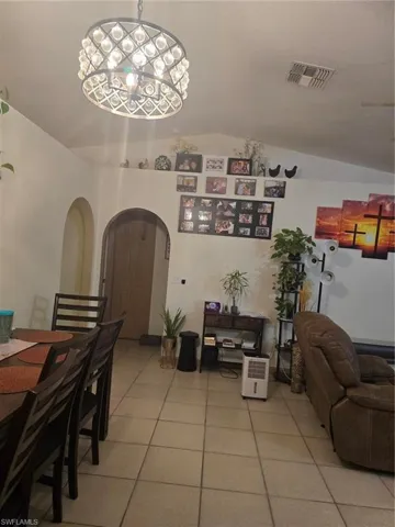 Tiled dining area featuring lofted ceiling and a chandelier