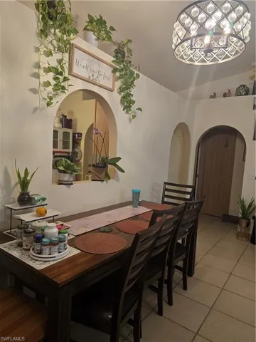Dining space with light tile patterned floors and an inviting chandelier