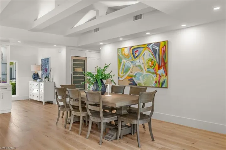 Dining space with high vaulted ceiling and light hardwood / wood-style flooring