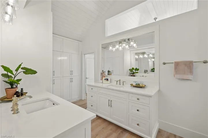 Bathroom featuring vaulted ceiling, hardwood / wood-style flooring, oversized vanity, and double sink