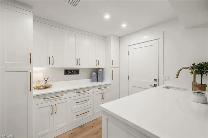 Kitchen featuring sink, white cabinets, and light hardwood / wood-style flooring