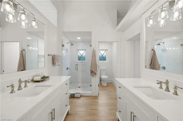 Bathroom with an enclosed shower, vanity, toilet, and wood-type flooring