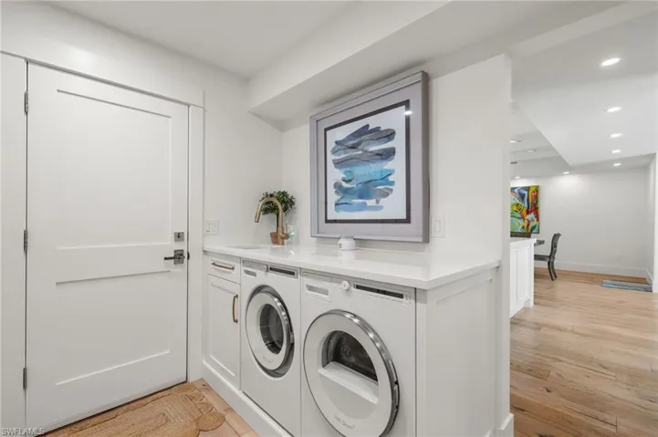 Washroom featuring sink, cabinets, light wood-type flooring, and washing machine and clothes dryer
