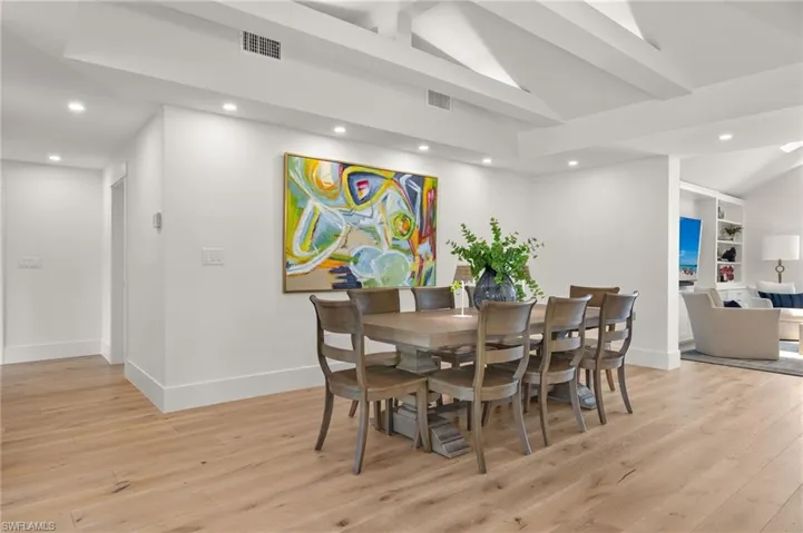 Dining area with lofted ceiling with beams, built in shelves, and light hardwood / wood-style flooring