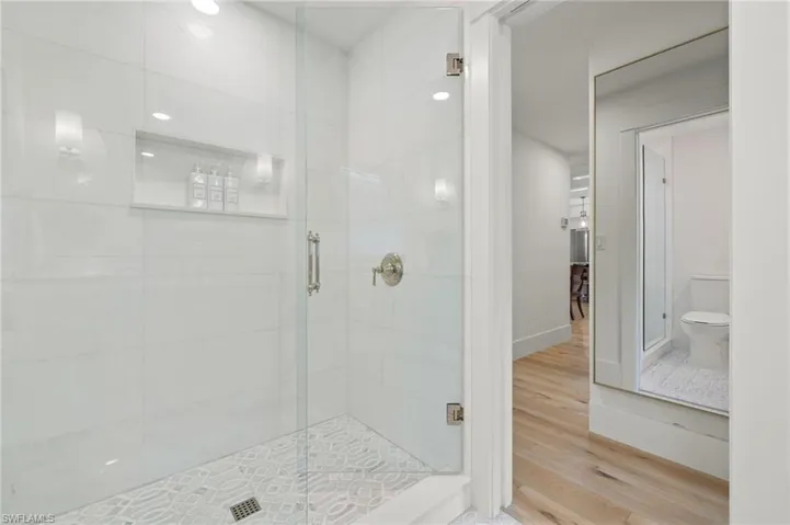 Bathroom featuring walk in shower, hardwood / wood-style flooring, and toilet