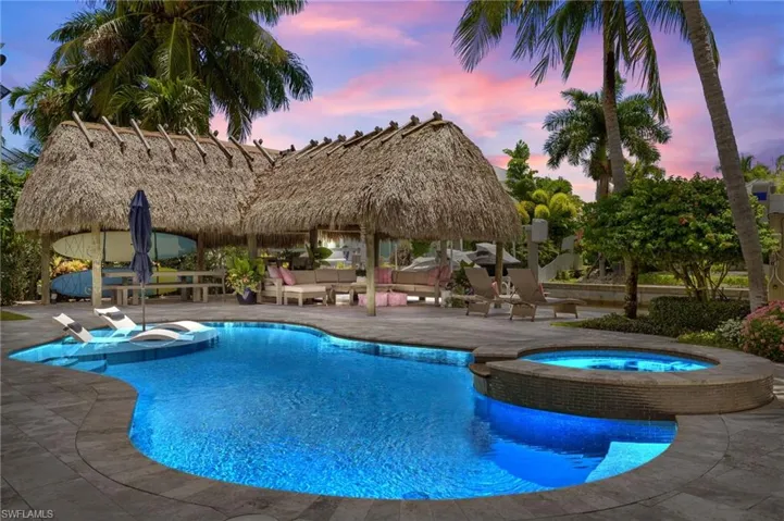 Pool at dusk with a patio area, an in ground hot tub, and a gazebo