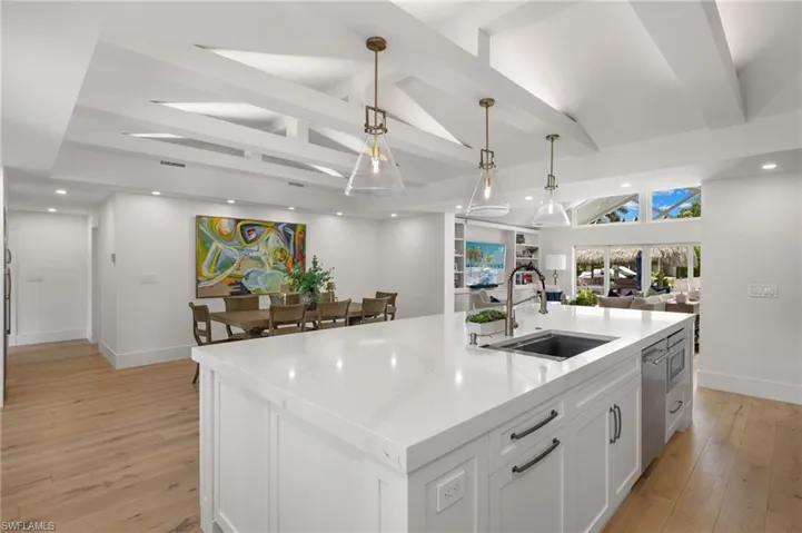 Kitchen featuring hanging light fixtures, an island with sink, light hardwood / wood-style floors, and white cabinets