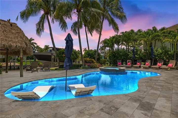 Pool at dusk with a patio and an in ground hot tub