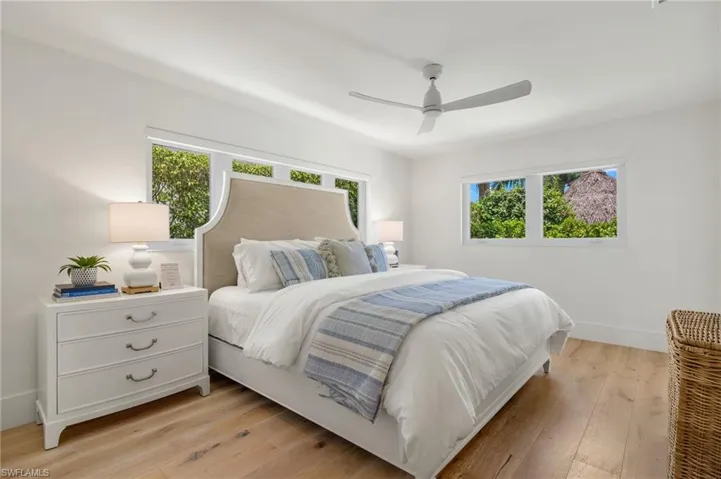 Bedroom with ceiling fan, multiple windows, and light hardwood / wood-style floors