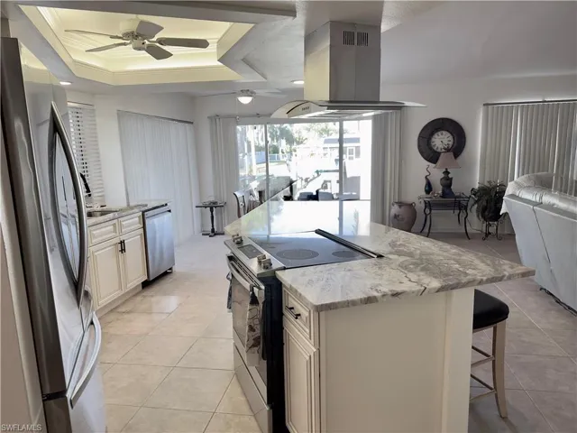 Kitchen with open floor plan, stainless steel appliances, island exhaust hood, a breakfast bar, and a center island