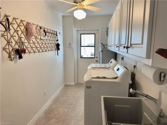 Laundry room with cabinet space, washer and dryer, light tile patterned floors, ceiling fan, and water heater