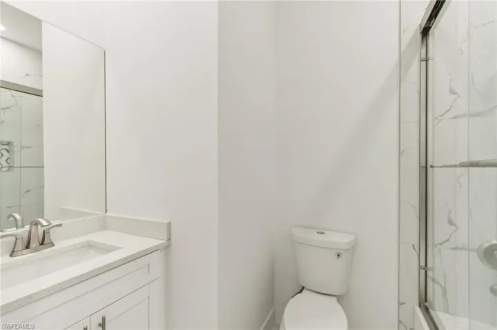 Bathroom with vanity, toilet, and an enclosed shower