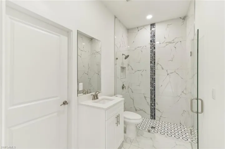 Bathroom with vanity, toilet, and an enclosed shower