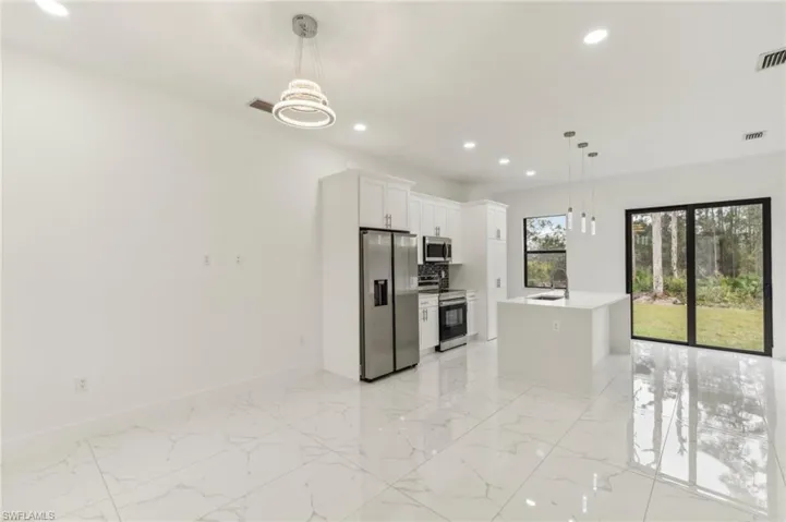 Kitchen featuring white cabinetry, a center island, hanging light fixtures, and appliances with stainless steel finishes