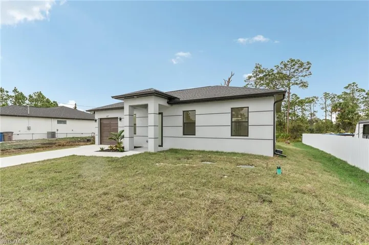 View of front facade with central AC unit, a garage, and a front lawn