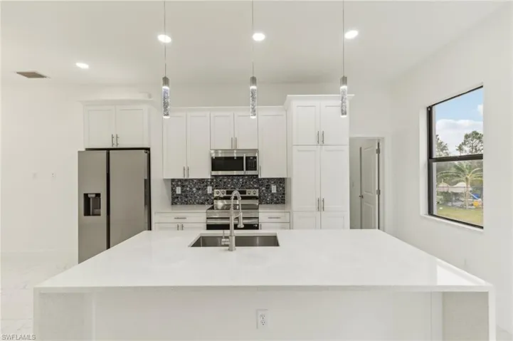 Kitchen featuring pendant lighting, white cabinets, and stainless steel appliances