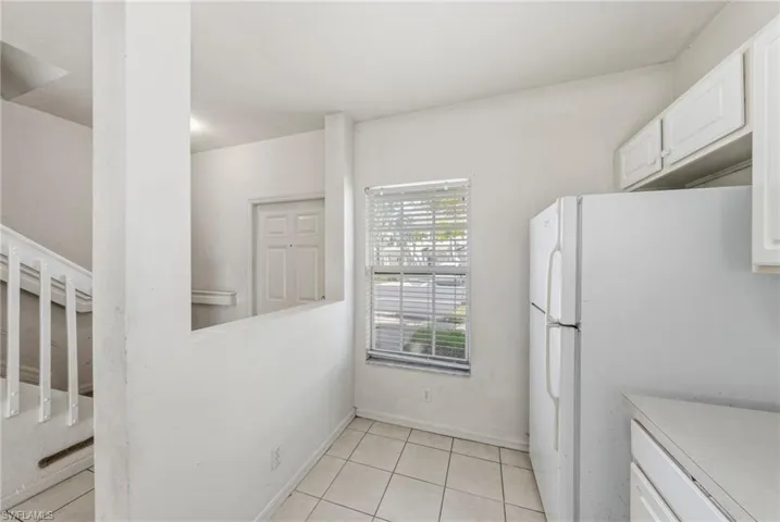 Kitchen with freestanding refrigerator, white cabinets, light countertops, and light tile patterned floors