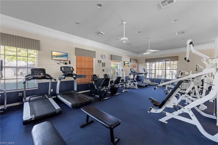 Gym with ornamental molding and a ceiling fan