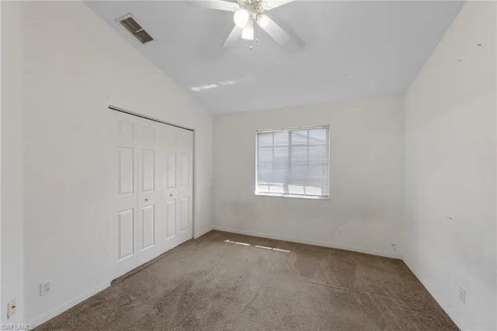 Unfurnished bedroom featuring lofted ceiling, carpet, a closet, and ceiling fan