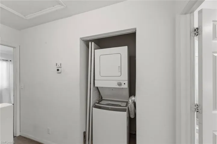 Laundry room featuring stacked washer and clothes dryer and attic access